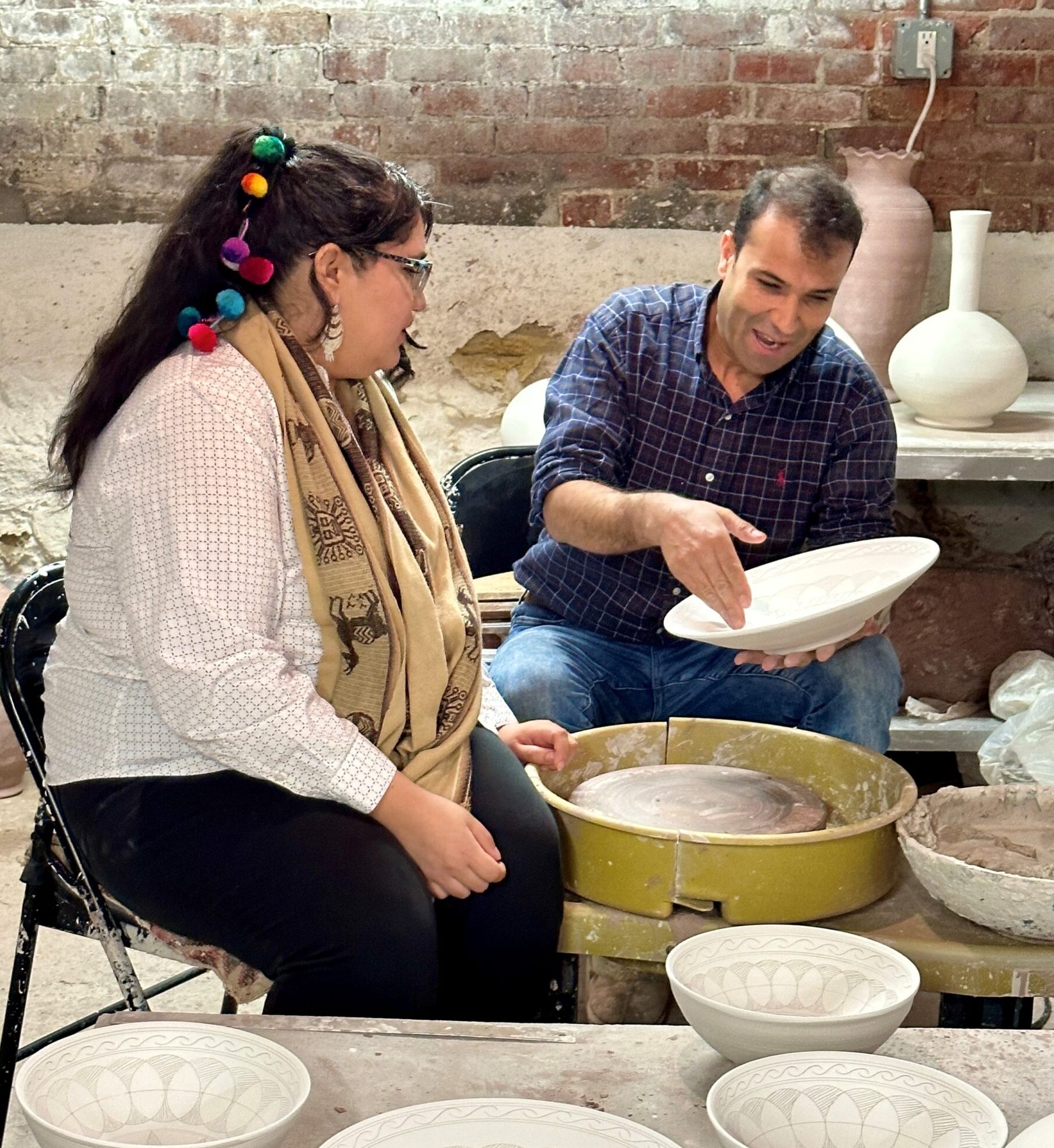 Man showing young woman how to make pottery